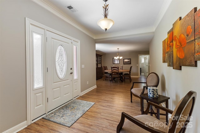 foyer featuring visible vents, crown molding, baseboards, light wood-style flooring, and a notable chandelier