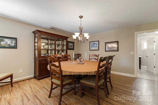 dining room with visible vents, baseboards, a chandelier, and light wood finished floors