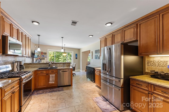 kitchen with stainless steel appliances, visible vents, a peninsula, and brown cabinetry