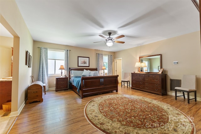 bedroom with a ceiling fan, visible vents, wood finished floors, and baseboards