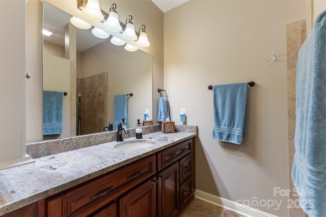 bathroom featuring tiled shower, vanity, and baseboards