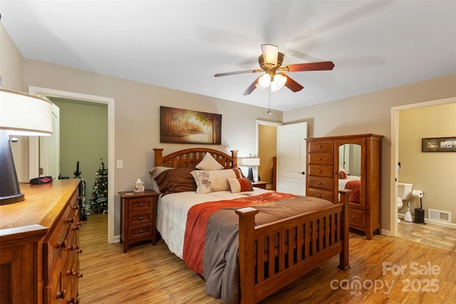 bedroom with connected bathroom, visible vents, light wood-style floors, and ceiling fan