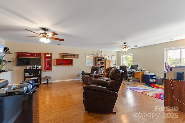 living area with a ceiling fan, visible vents, wood finished floors, and baseboards