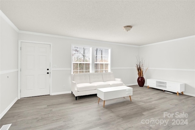 living area with wood-type flooring, a textured ceiling, and ornamental molding