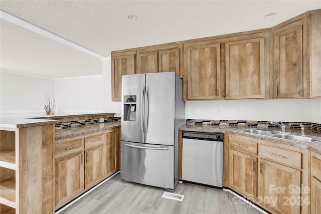 kitchen with light wood-type flooring, a textured ceiling, stainless steel appliances, crown molding, and sink