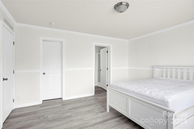 unfurnished bedroom featuring a textured ceiling, light hardwood / wood-style floors, and crown molding