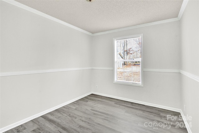 empty room featuring hardwood / wood-style floors, ornamental molding, and a textured ceiling