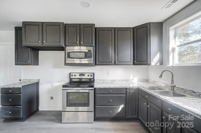 kitchen featuring light hardwood / wood-style flooring, stainless steel appliances, light stone counters, and sink