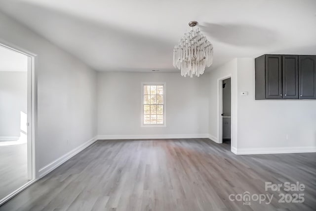 unfurnished dining area with wood-type flooring and an inviting chandelier