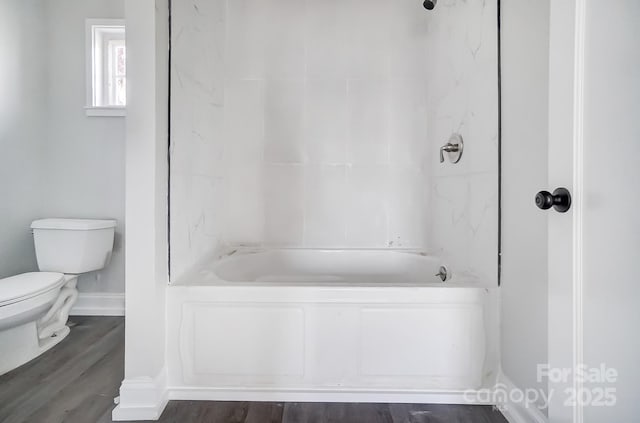 bathroom with wood-type flooring, shower / bathtub combination, and toilet