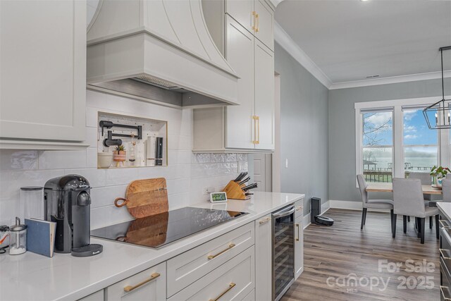 kitchen featuring pendant lighting, white cabinets, beverage cooler, black electric stovetop, and custom range hood