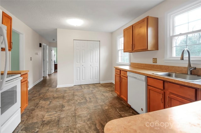 kitchen featuring a textured ceiling, plenty of natural light, white appliances, and sink