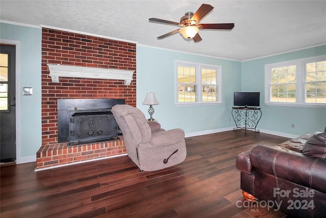 living room featuring dark hardwood / wood-style floors, a brick fireplace, ceiling fan, and crown molding