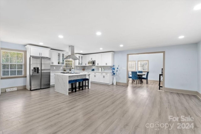 kitchen featuring island exhaust hood, appliances with stainless steel finishes, a center island, and light hardwood / wood-style floors