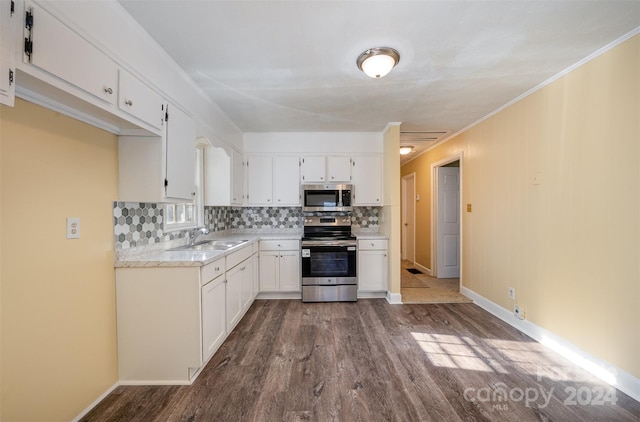 kitchen featuring appliances with stainless steel finishes, crown molding, sink, hardwood / wood-style floors, and white cabinetry