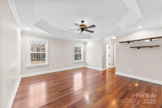 unfurnished room with a tray ceiling, crown molding, ceiling fan, and dark wood-type flooring