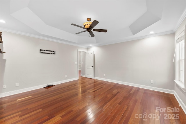 spare room with a raised ceiling, ceiling fan, wood-type flooring, and ornamental molding