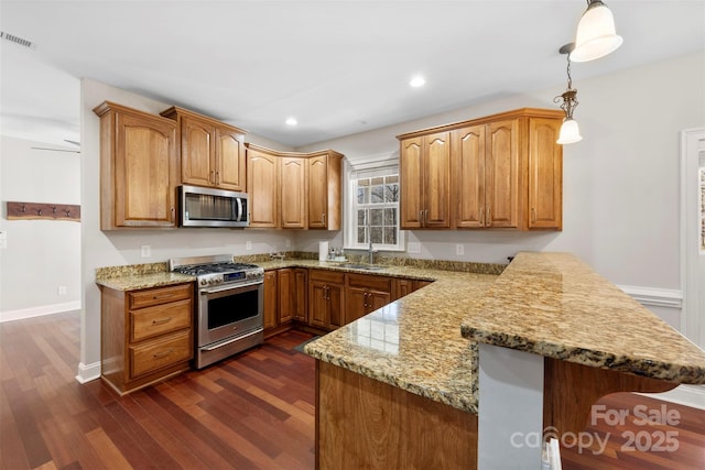 kitchen with kitchen peninsula, pendant lighting, stainless steel appliances, and sink