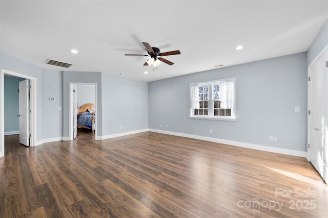 interior space with a walk in closet, ensuite bath, ceiling fan, dark hardwood / wood-style floors, and a closet