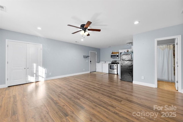 unfurnished living room with washer and clothes dryer, ceiling fan, and hardwood / wood-style flooring