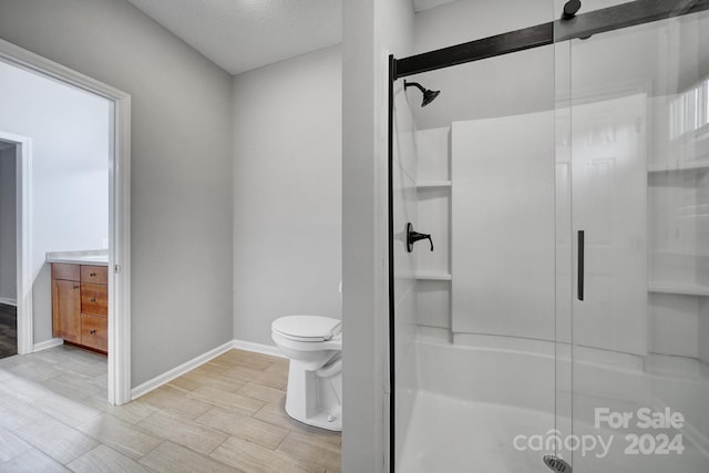 bathroom featuring a textured ceiling, vanity, toilet, and walk in shower