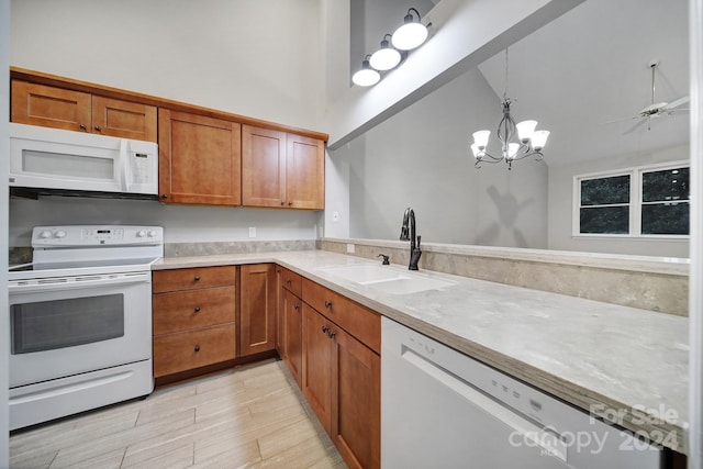 kitchen featuring white appliances, a high ceiling, ceiling fan with notable chandelier, sink, and hanging light fixtures