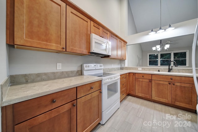 kitchen featuring ceiling fan with notable chandelier, white appliances, sink, decorative light fixtures, and high vaulted ceiling