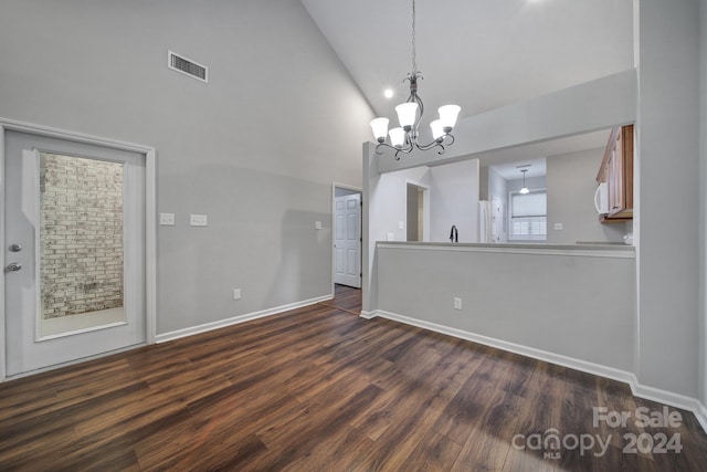 unfurnished dining area featuring an inviting chandelier, high vaulted ceiling, dark wood-type flooring, and sink