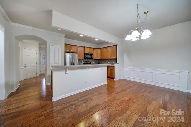 kitchen with a center island, stainless steel fridge, a chandelier, pendant lighting, and ornamental molding