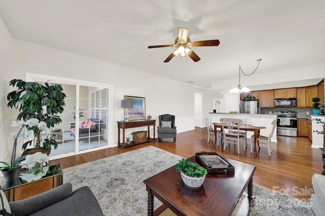 living area featuring dark wood finished floors and ceiling fan with notable chandelier