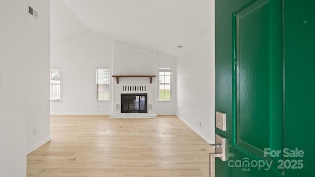 unfurnished living room with a fireplace, visible vents, light wood-style floors, high vaulted ceiling, and baseboards