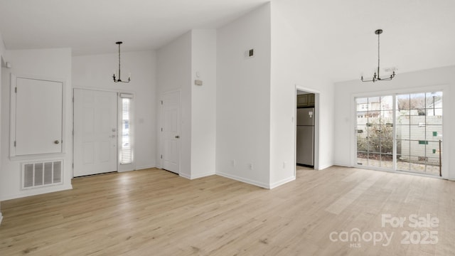 foyer entrance with a healthy amount of sunlight, an inviting chandelier, visible vents, and high vaulted ceiling