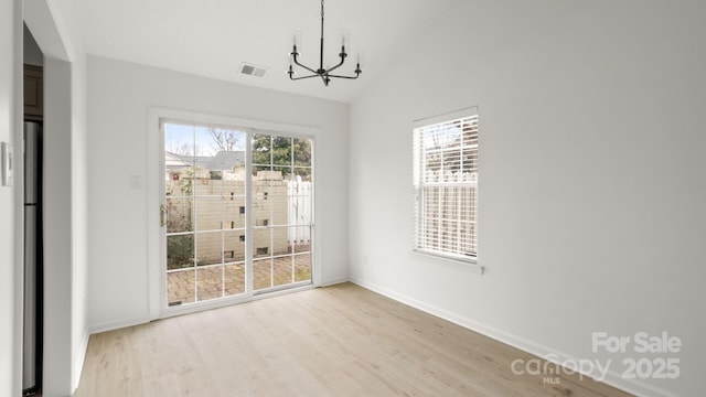 unfurnished dining area featuring visible vents, light wood-style floors, vaulted ceiling, a chandelier, and baseboards