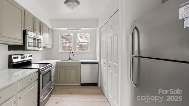 kitchen featuring light wood-type flooring, a sink, stainless steel appliances, and light countertops