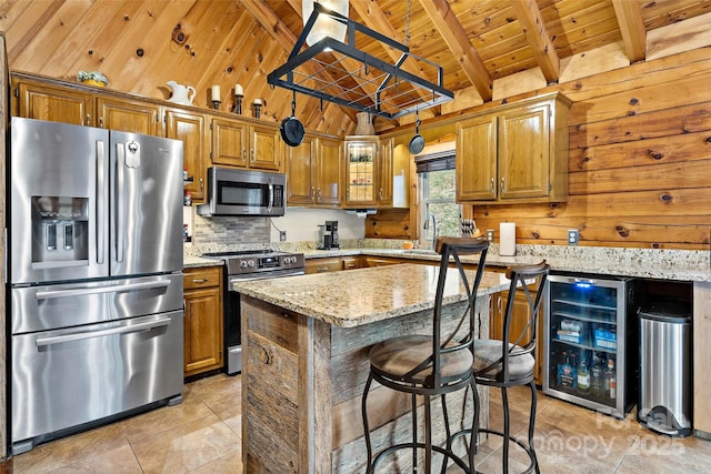 kitchen featuring light stone countertops, stainless steel appliances, beverage cooler, wooden ceiling, and a kitchen island