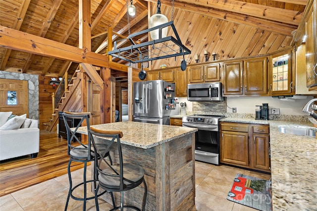 kitchen with beam ceiling, light stone countertops, sink, light tile patterned floors, and appliances with stainless steel finishes