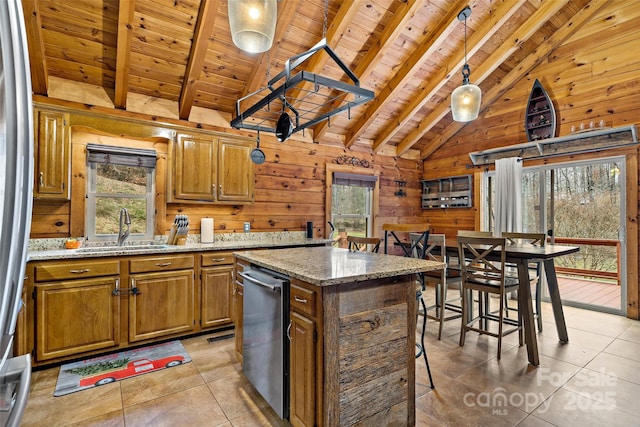 kitchen featuring light stone countertops, wood ceiling, sink, a kitchen island, and wood walls