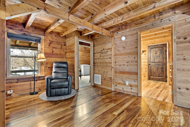 living area with hardwood / wood-style floors, wood walls, wooden ceiling, and beam ceiling