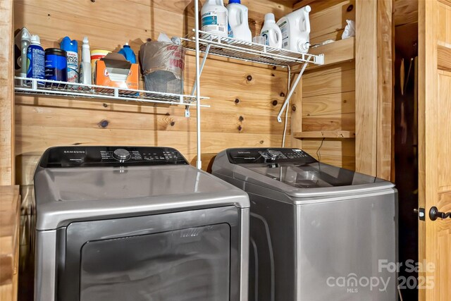 laundry room with washing machine and dryer and wood walls