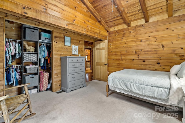 carpeted bedroom with lofted ceiling with beams, a closet, wooden walls, and wood ceiling