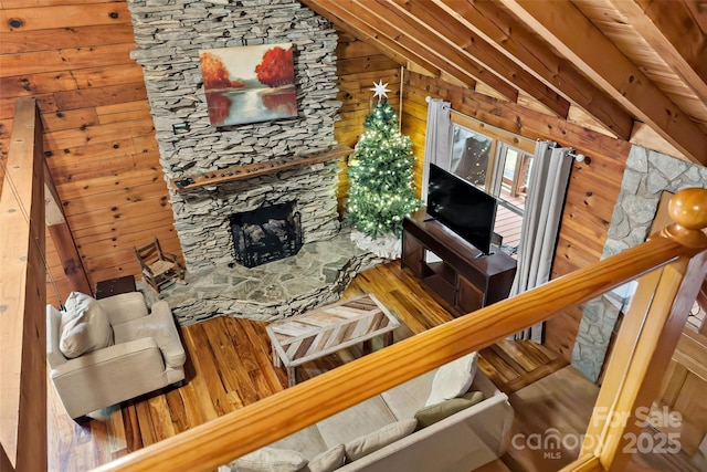 living room with a stone fireplace, wooden walls, lofted ceiling, and hardwood / wood-style flooring