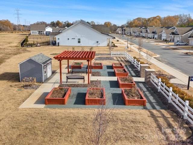 exterior space featuring an outbuilding, a garden, a residential view, and a storage unit