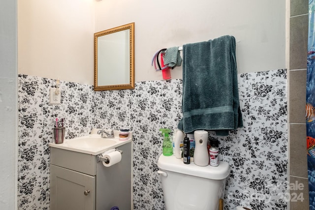 bathroom with vanity, toilet, and tile walls