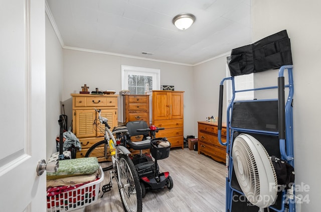 exercise room with crown molding and light wood-type flooring