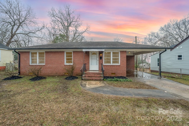 view of front of property with brick siding, driveway, crawl space, a carport, and a front lawn