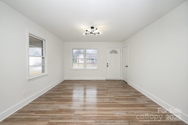 interior space with a notable chandelier, light wood-type flooring, and baseboards