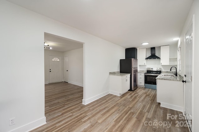 kitchen with baseboards, wall chimney exhaust hood, appliances with stainless steel finishes, light wood-type flooring, and a sink