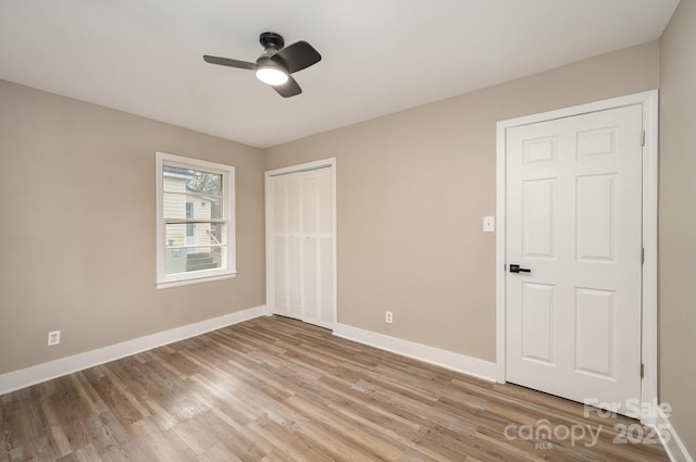 unfurnished bedroom featuring light wood finished floors, a ceiling fan, baseboards, and a closet