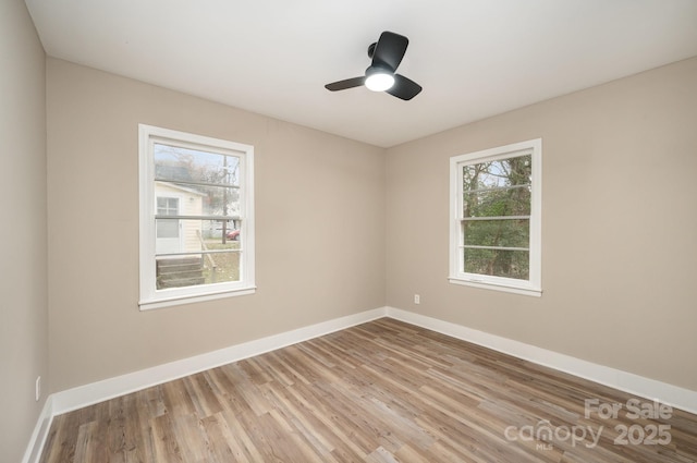 spare room featuring a healthy amount of sunlight, light wood-style floors, and baseboards