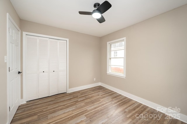 unfurnished bedroom with a ceiling fan, a closet, light wood-style flooring, and baseboards